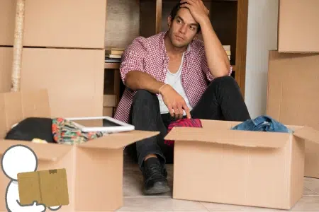 Uomo preoccupato in mezzo a scatoloni per cambio casa